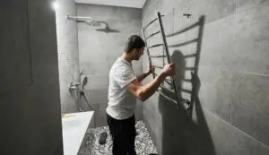 Man installing electric heated towel rack in bathroom.